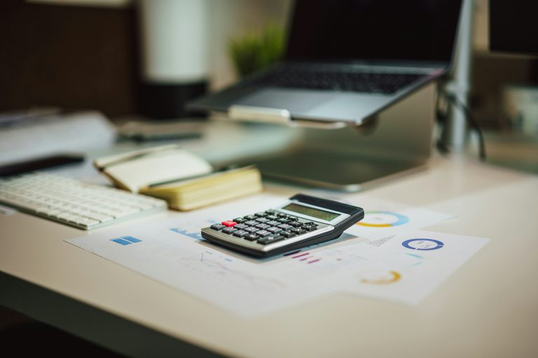 Calculadora junto a un portátil y documentación de trabajo
